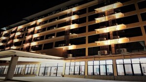 A multi-story hotel with a modern design, featuring balconies with railings and large windows.