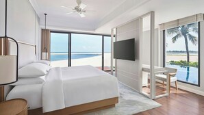 A bedroom with a bed, a TV, and a view of the beach. - Renaissance Danang Hoi An Resort & Spa (Da Nang)