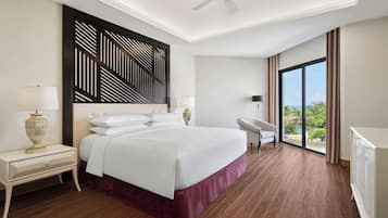 A hotel room with a large bed, a desk, a chair, a ceiling fan, and a view of the outdoors.
