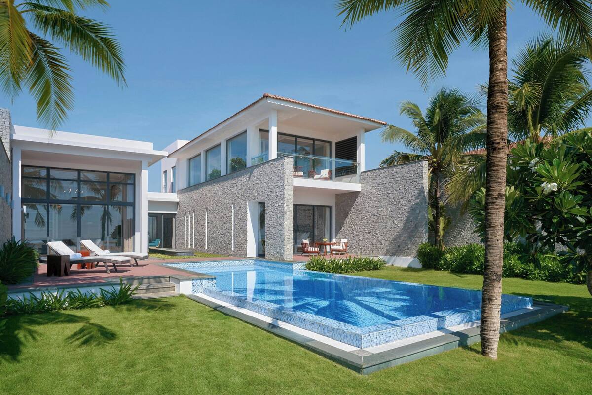 A modern two-story house with a swimming pool, large windows, and a stone facade.