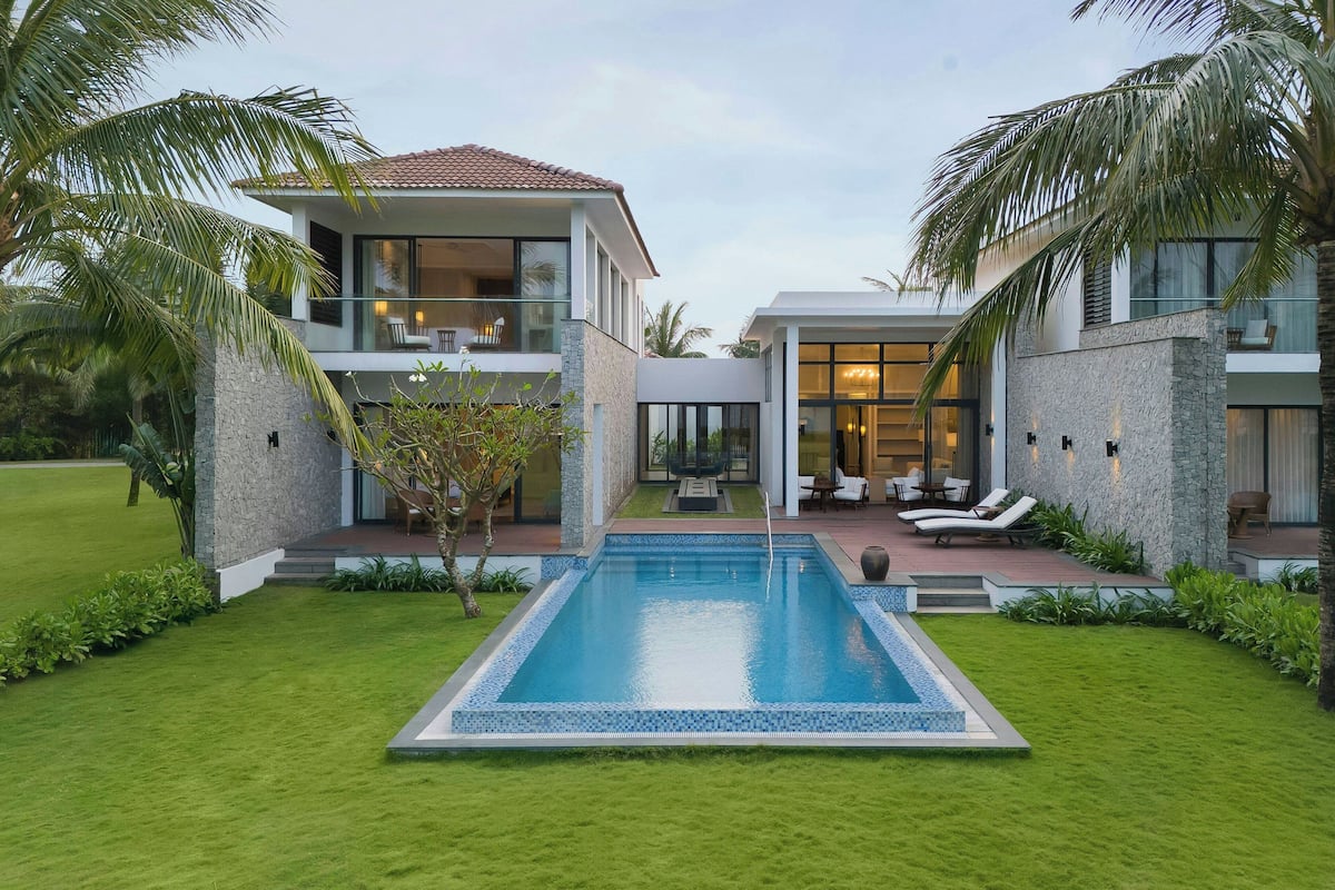 A modern two-story house with a swimming pool, outdoor seating, and a well-maintained lawn.