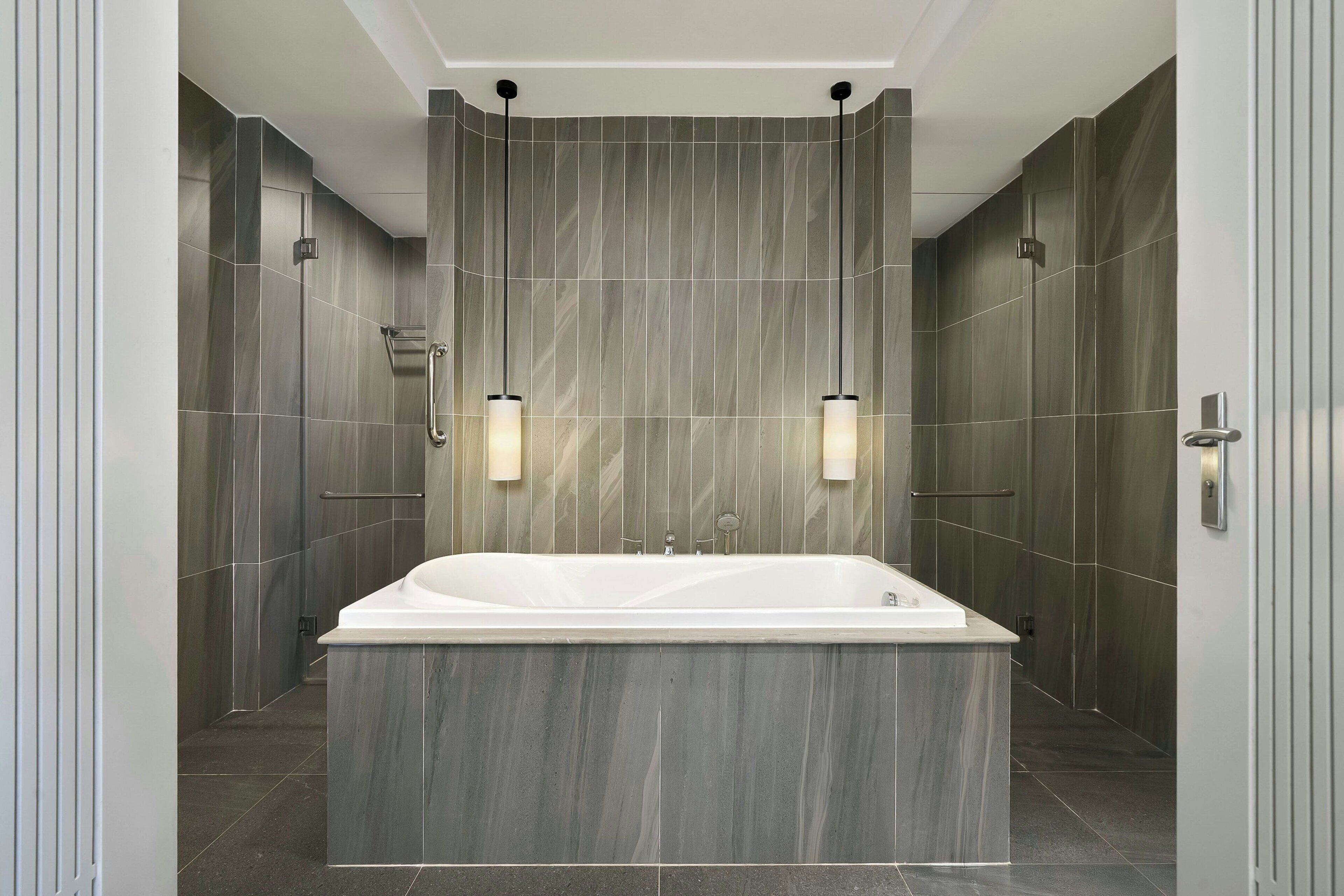 Un bagno moderno con una vasca da bagno indipendente ampia, portasci a muro e illuminazione a incasso.