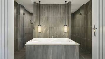 Un bagno moderno con una vasca da bagno indipendente ampia, portasci a muro e illuminazione a incasso.