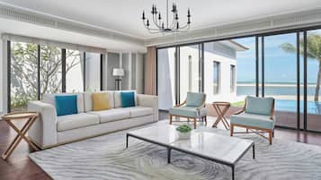 Una sala de estar moderna con un sofá, sillones, una mesa de centro y un ventanal con vistas a la playa.