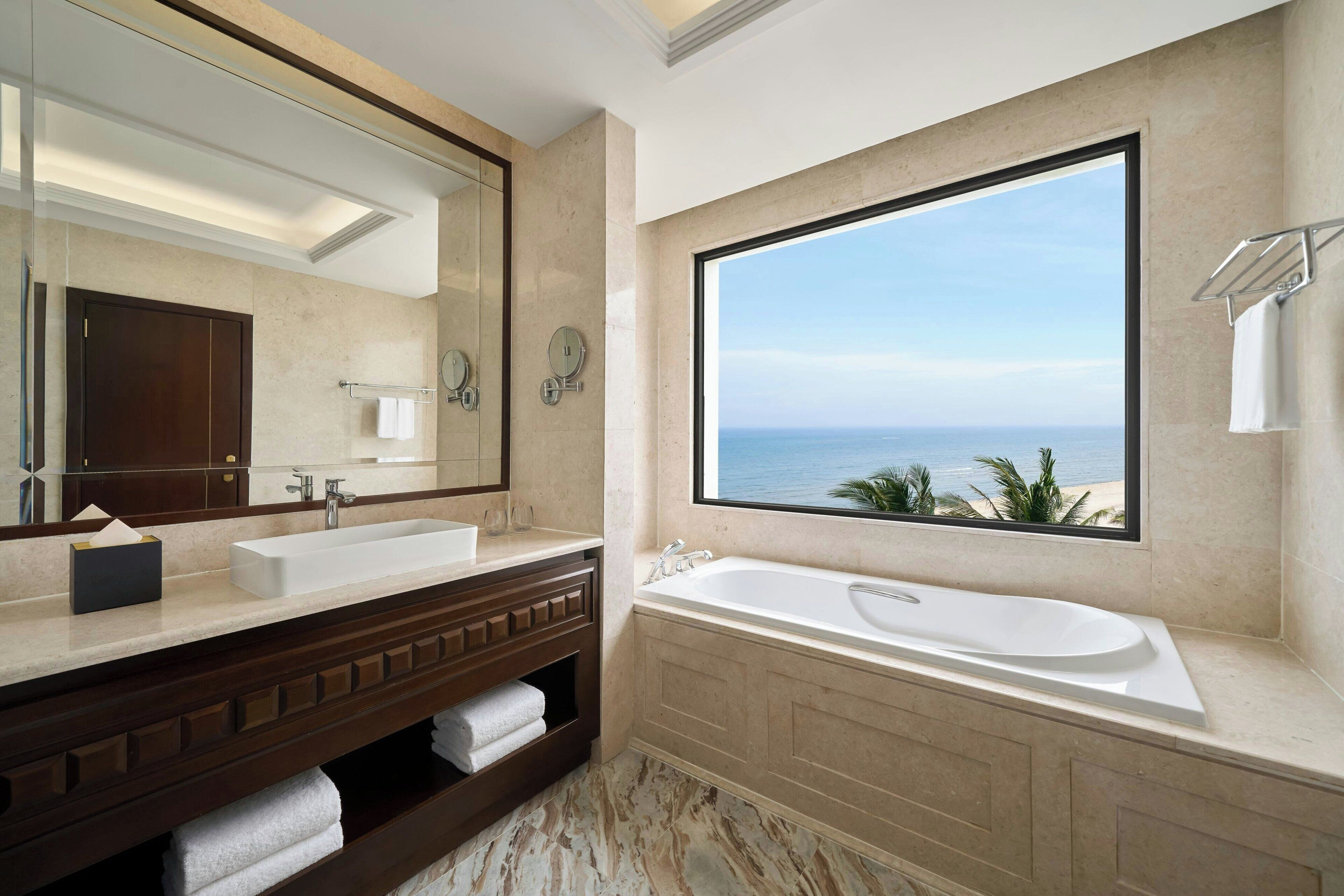 A bathroom with a large window, a bathtub, and a double sink.