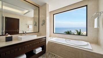 A bathroom with a large window, a bathtub, and a double sink.