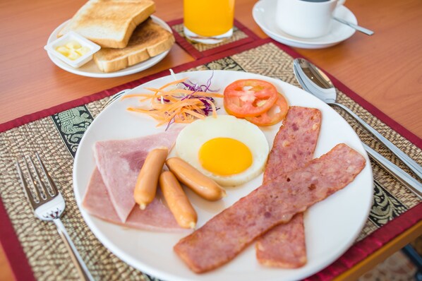 Prato de café da manhã com ovos, bacon, salsichas, presunto e legumes.