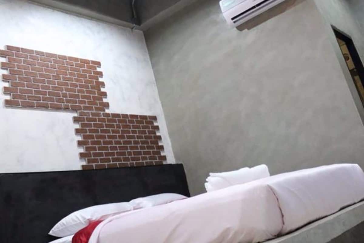 Een kamer met een bed, een plafondlamp en een airconditioning.