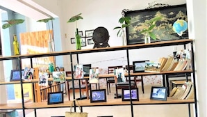A room with a wooden bookshelf displaying framed photos and books. - Rubis Hostel (Hue)