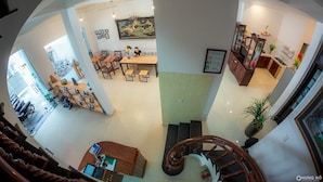 A spacious hotel lobby with a dining area, a staircase, and a view of the street. - Rubis Hostel (Hue)