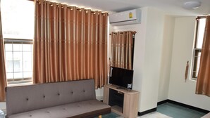 A living room with a sofa, television, and curtains.