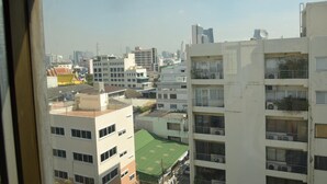 A view of a cityscape with multiple buildings, including a multi-story residential building with balconies and a rooftop sports field.