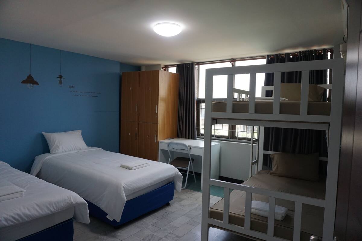 A room with two single beds, a desk, a wardrobe, and a bunk bed.
