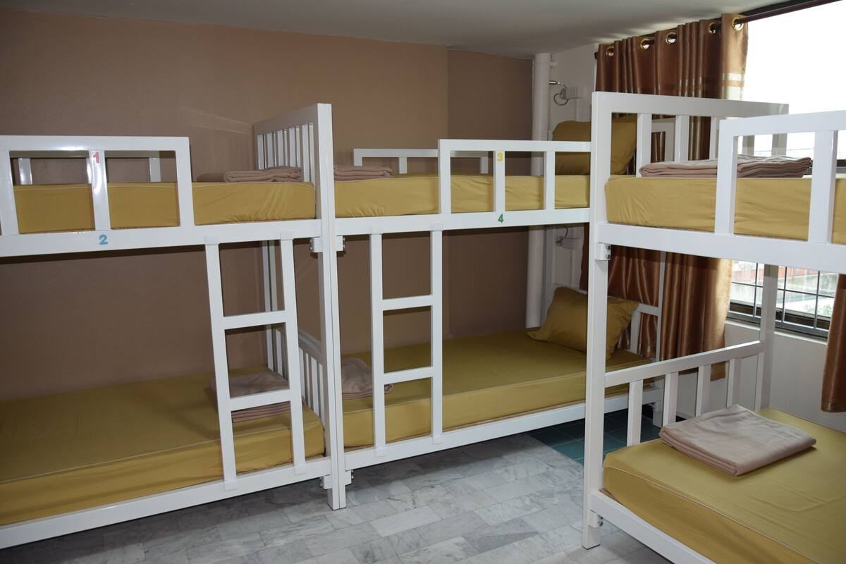 A bunk bed room with three levels, each with a yellow mattress and white frame.