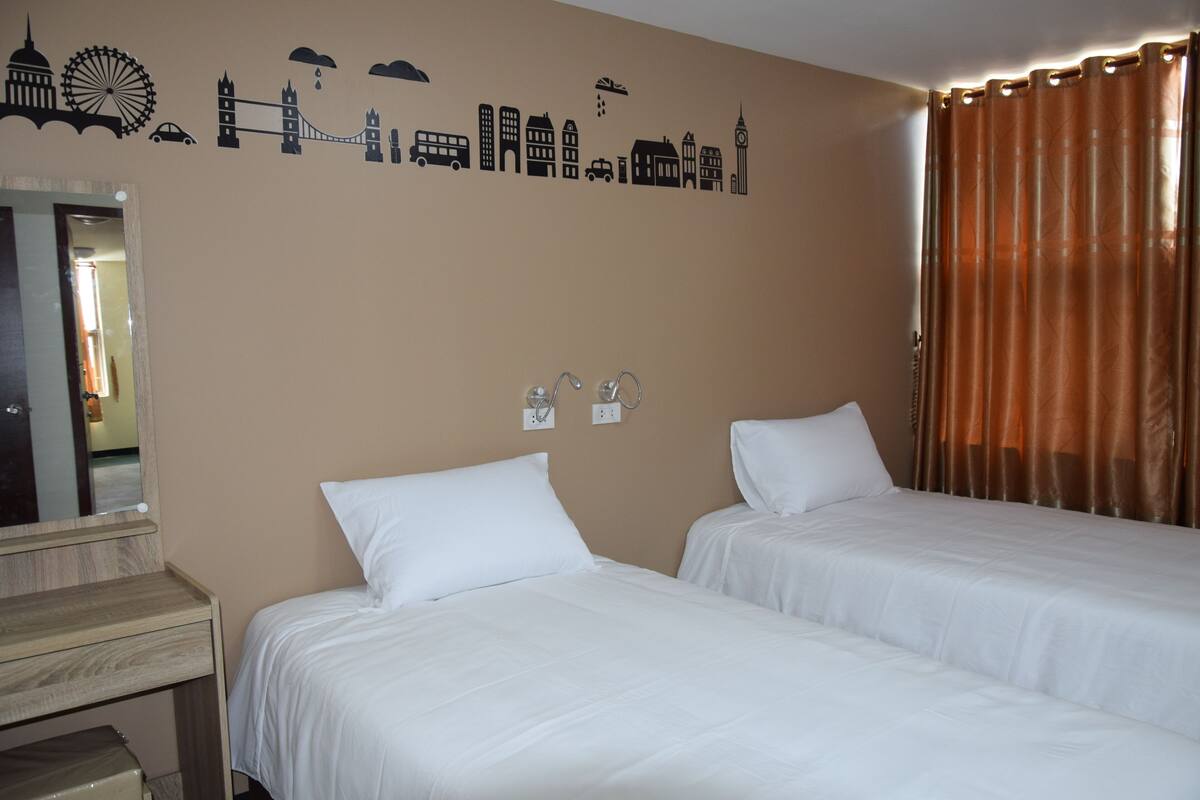 A hotel room with two beds, a mirror, and a wall with cityscape decals.