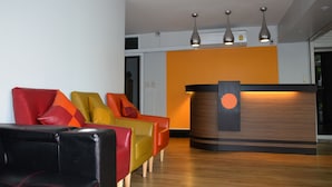 A reception area with a wooden reception desk, three pendant lights, and colorful chairs.