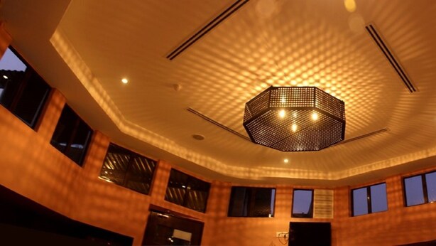 A modern interior with a hexagonal ceiling light fixture and multiple windows. - Rock & Roll Hotel (Klang)