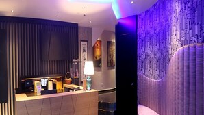 A modern hotel lobby with a reception desk, a seating area, and a wall with a cityscape mural. - Rock & Roll Hotel (Klang)