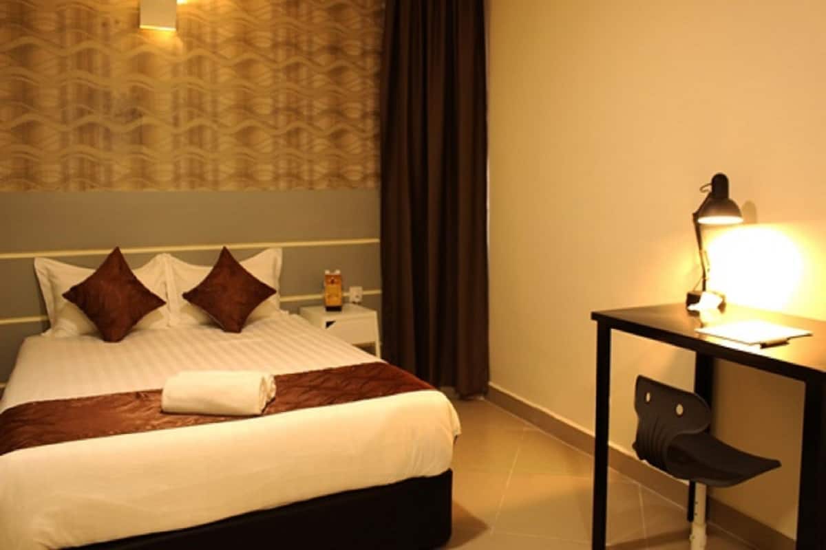 A hotel room with a bed, a desk, a chair, and a nightstand.