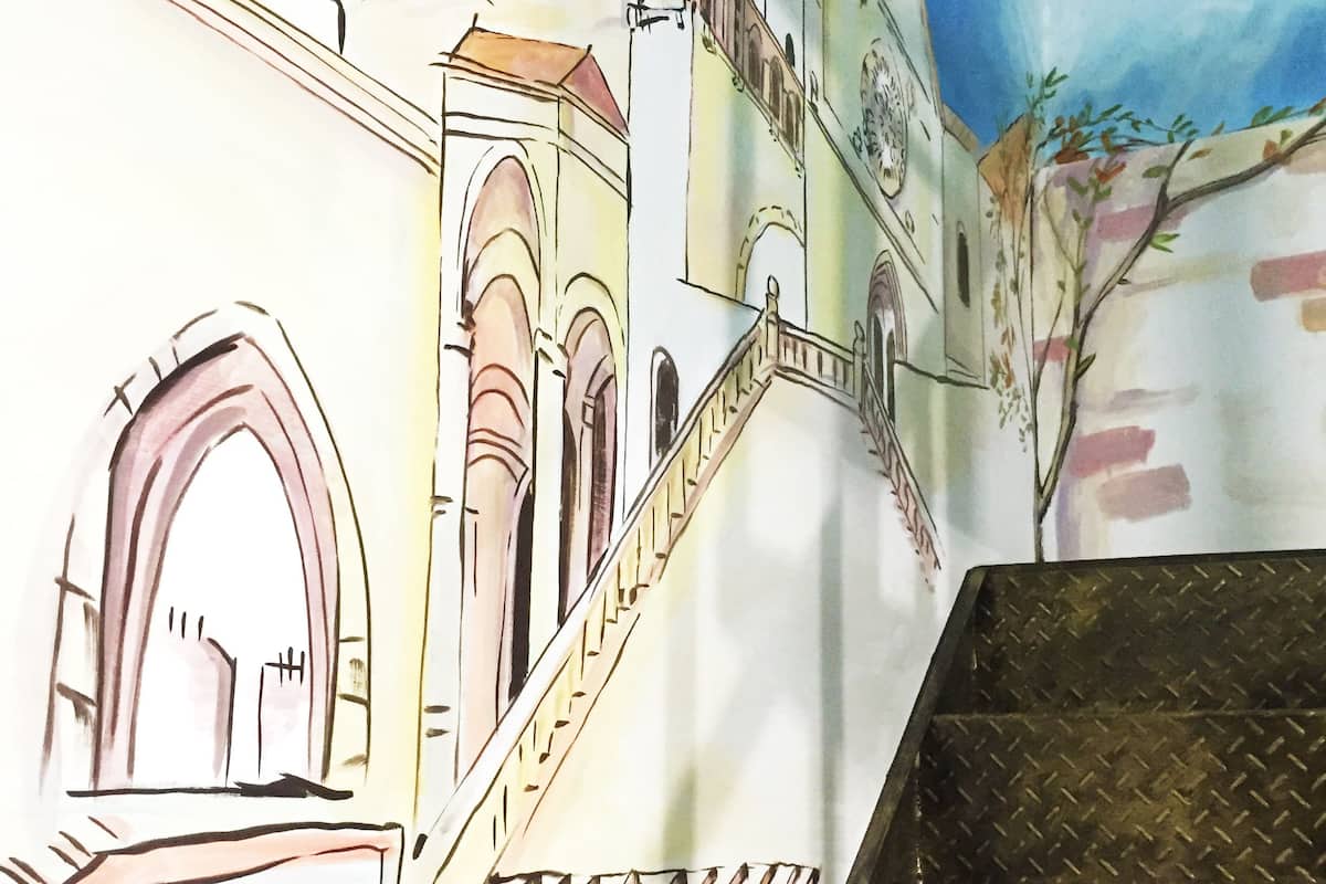 Um mural representando uma paisagem urbana com edifícios e uma escadaria.