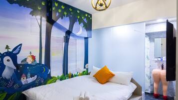 A bedroom with a bed, a night sky mural, a window with blinds, and a bathroom visible through an open door.