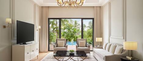 A modern living room with a TV, two armchairs, a sofa, a coffee table, and a chandelier.