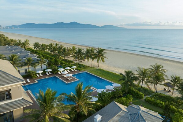 Un resort con piscina, playa y palmeras.