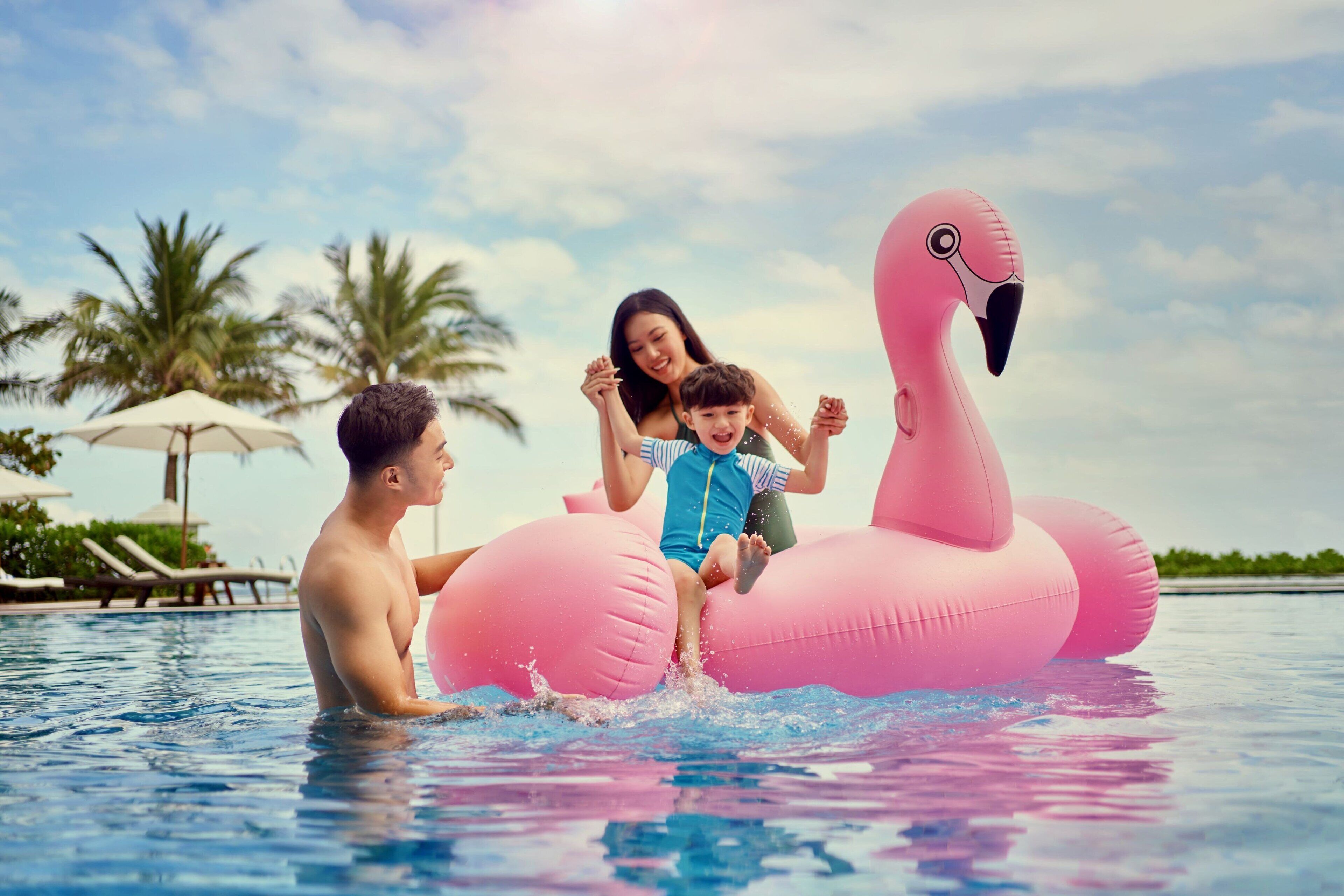 Eine Familie im Pool mit einem rosa Flamingo-Schwimmvogel.
