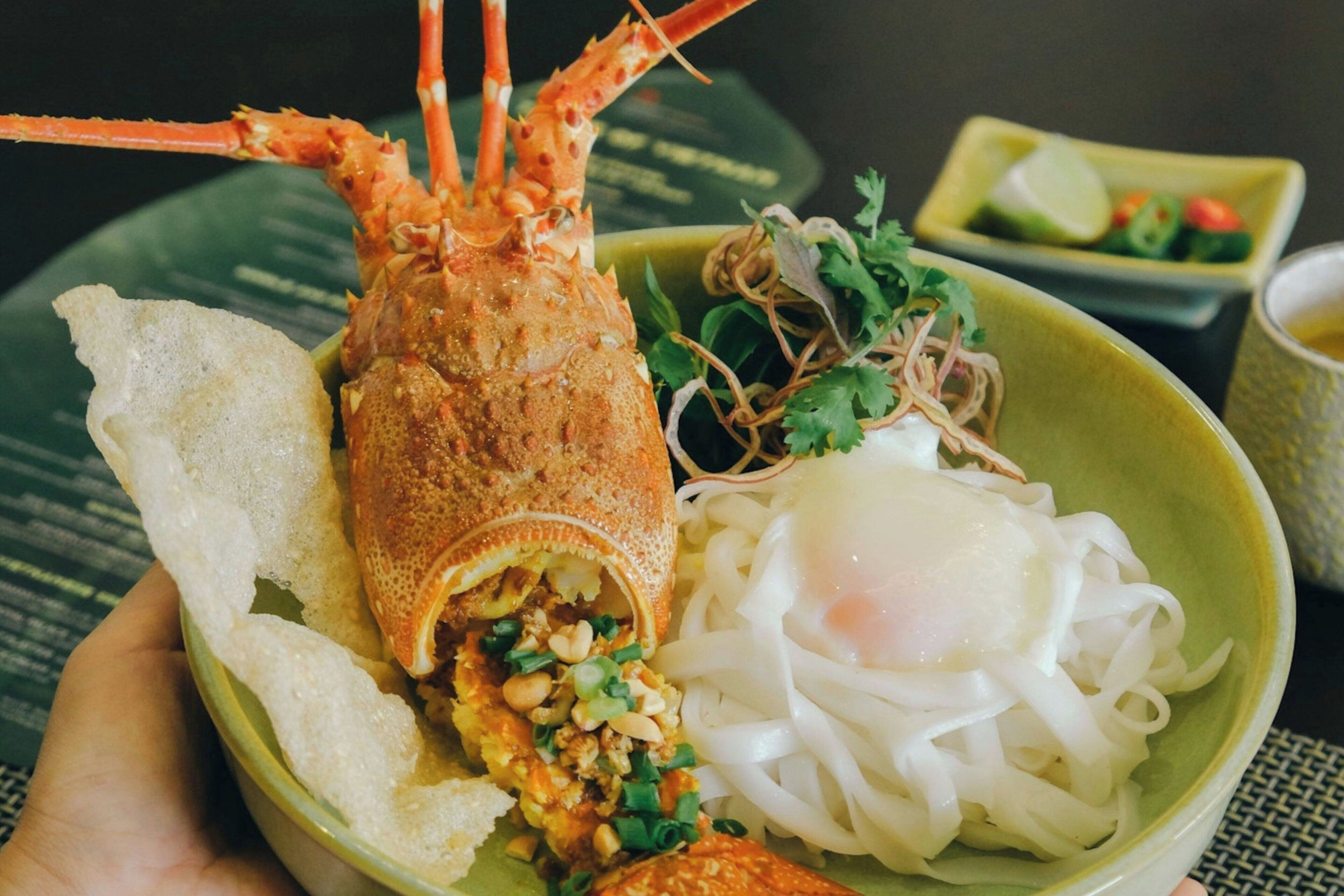 A plate with a lobster, noodles, and a poached egg.