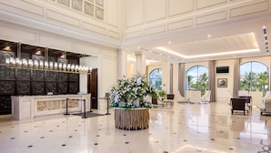 Un lobby amplio con un mostrador de recepción, un gran arreglo floral y un techo alto con diseños intrincados.