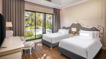 A hotel room with two beds, a desk, and a view of a tropical garden.