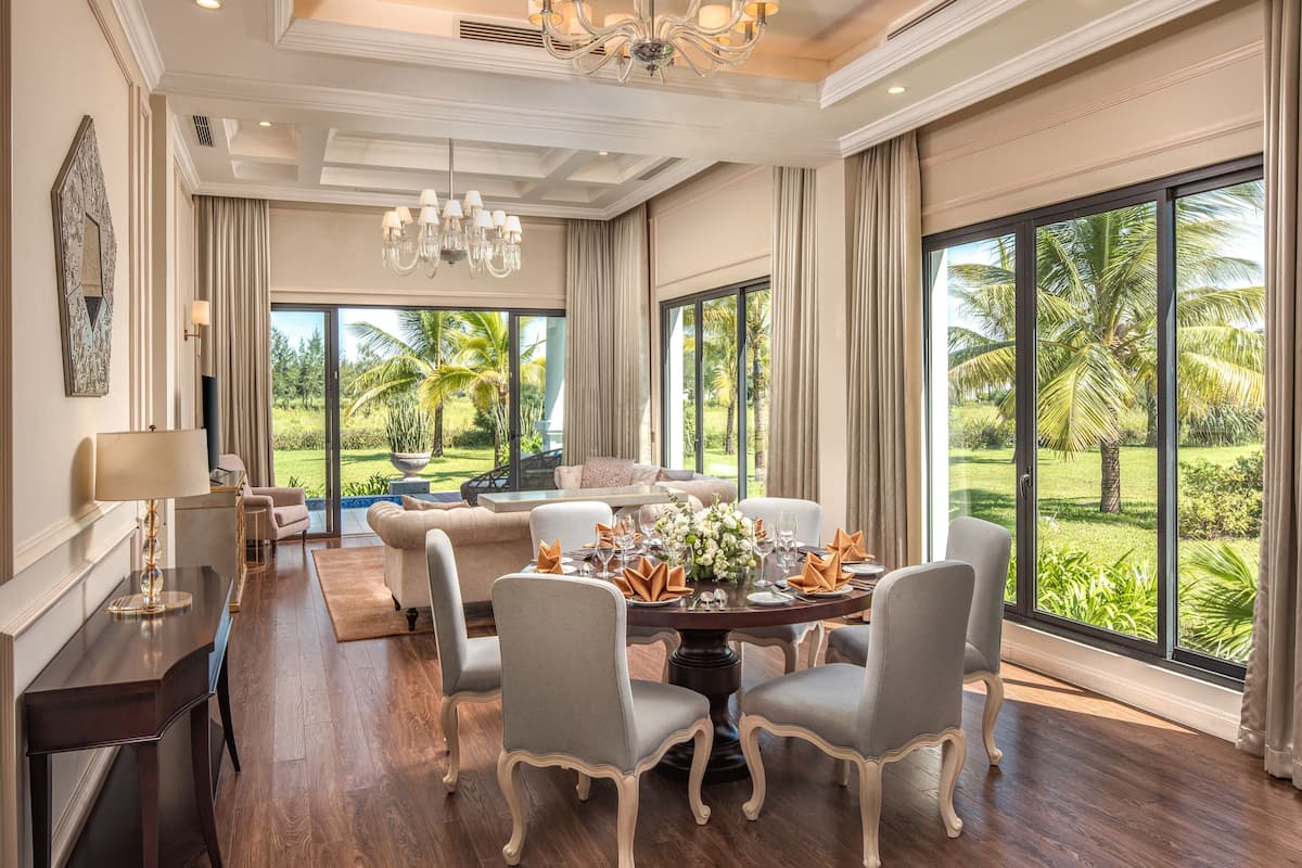 A spacious dining area with a large window offering a view of palm trees and a lawn.
