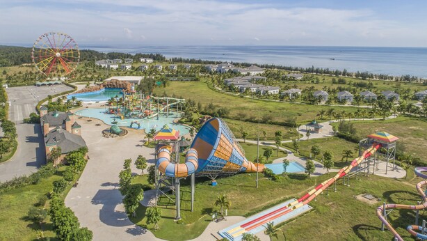 Vista aérea de un parque temático con tobogán acuático, noria y una amplia zona de piscina.