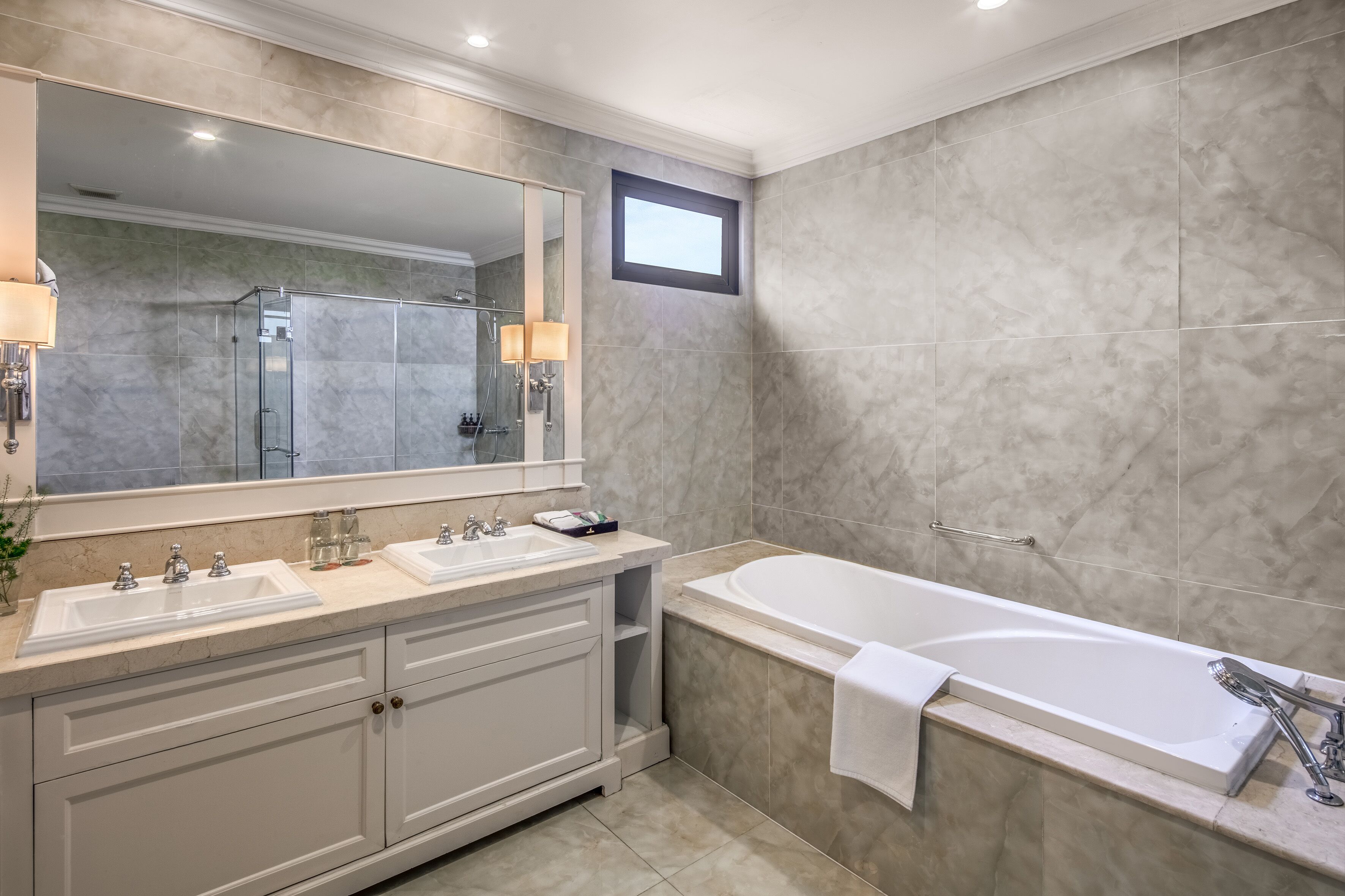 Un baño moderno con un espejo grande, dos lavamanos, una bañera y una zona de ducha.