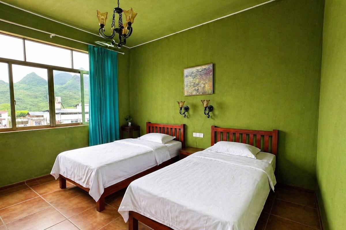 A room with two beds, a window with a view of mountains, a chandelier, and a painting on the wall.