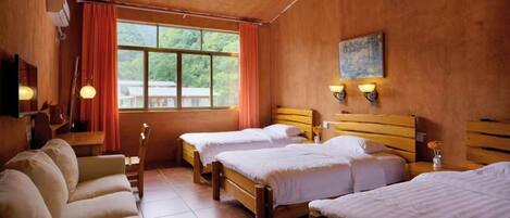 A hotel room with two beds, a sofa, a TV, and a window with curtains.