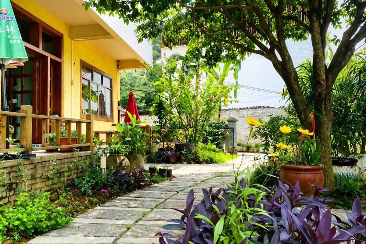 A yellow building with a wooden deck and potted plants.