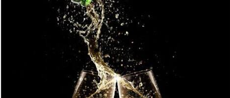 A champagne bottle being poured into two glasses, creating a splash.