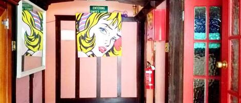 Un pasillo con una puerta roja, un extintor y un cartel que dice "ENTERING SWEET HOME".