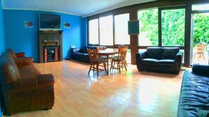 A living room with a fireplace, a TV, a dining table with chairs, and a sofa. - St Kilda East backpackers' hostel (St. Kilda East)