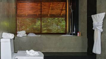 Ein Badezimmer mit Toilette, einem Fenster mit Jalousien, einer Dusche und einem Handtuchhalter.