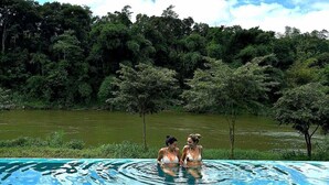A swimming pool with clear blue water, surrounded by lush greenery and trees. - Kandy Cabana Eco Resort (Weligalla)