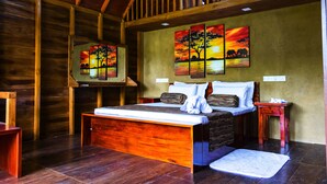 A wooden room with a bed, a nightstand, and a painting on the wall. - Kandy Cabana Eco Resort (Weligalla)