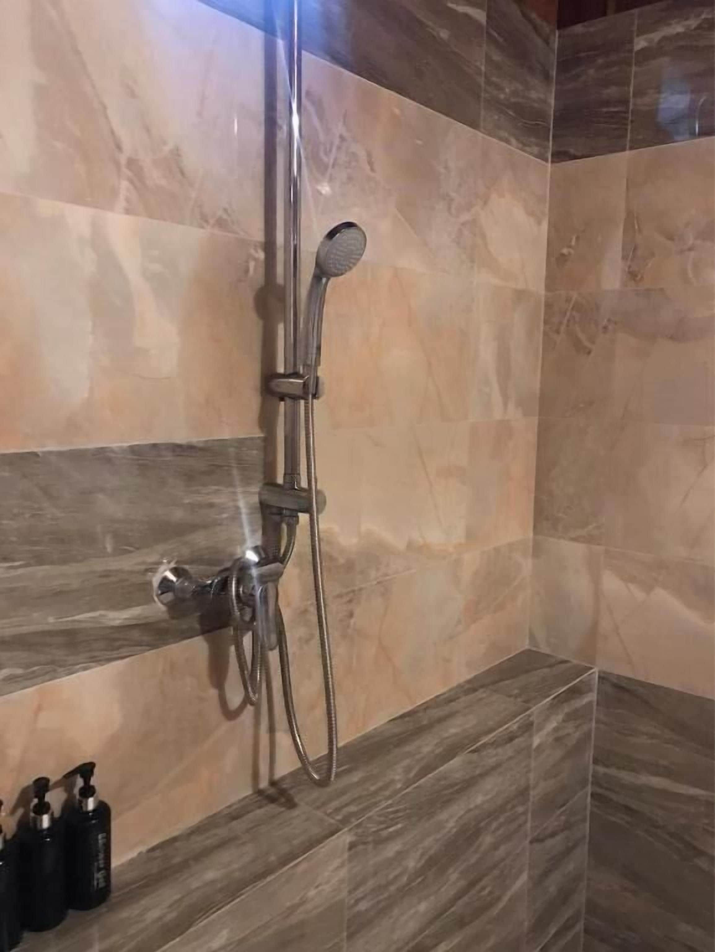 Eine Dusche mit Handbrause und Armaturen an der Wand.