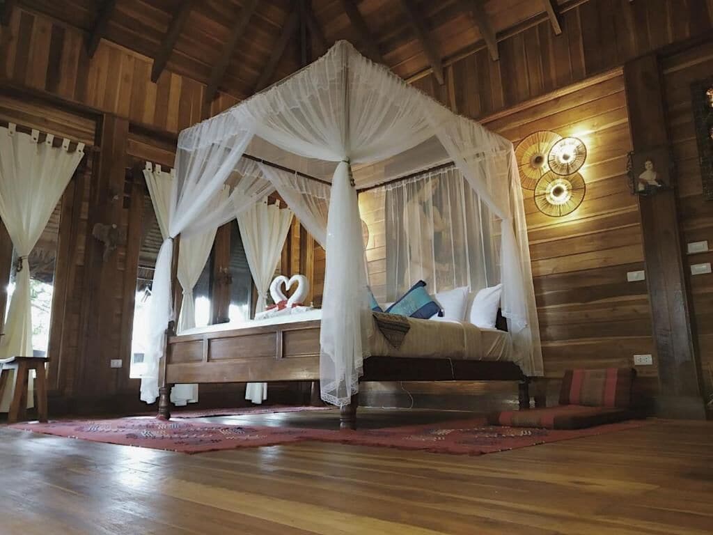 Une pièce en bois avec un lit à baldaquin, un plancher en bois et une horloge murale.