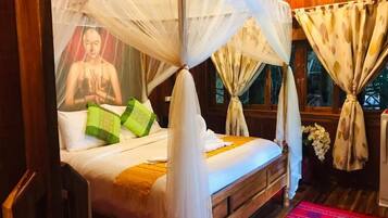 A bed with a canopy, pillows, a red patterned rug, and curtains.