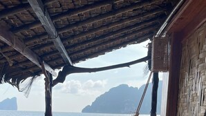 A hammock under a thatched roof, a tiled floor, and a view of the sea with mountains in the background. - Viking Nature Resort (Ko Phi Phi)