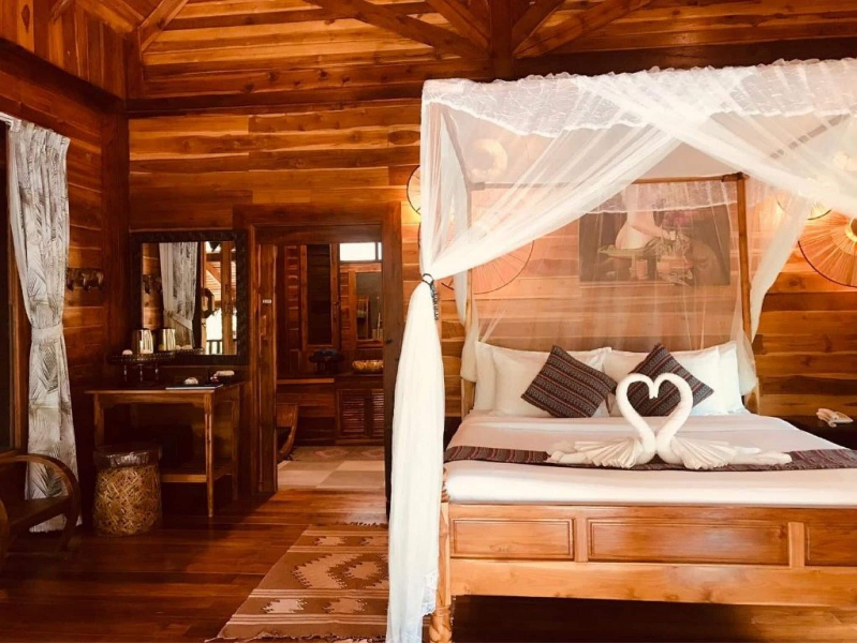 Une chambre dans un chalet en bois, avec un lit à baldaquin, un bureau et un miroir.