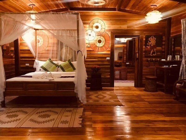 A wooden cabin-style room with a bed, a small table, and a mirror. - Viking Nature Resort (Ko Phi Phi)