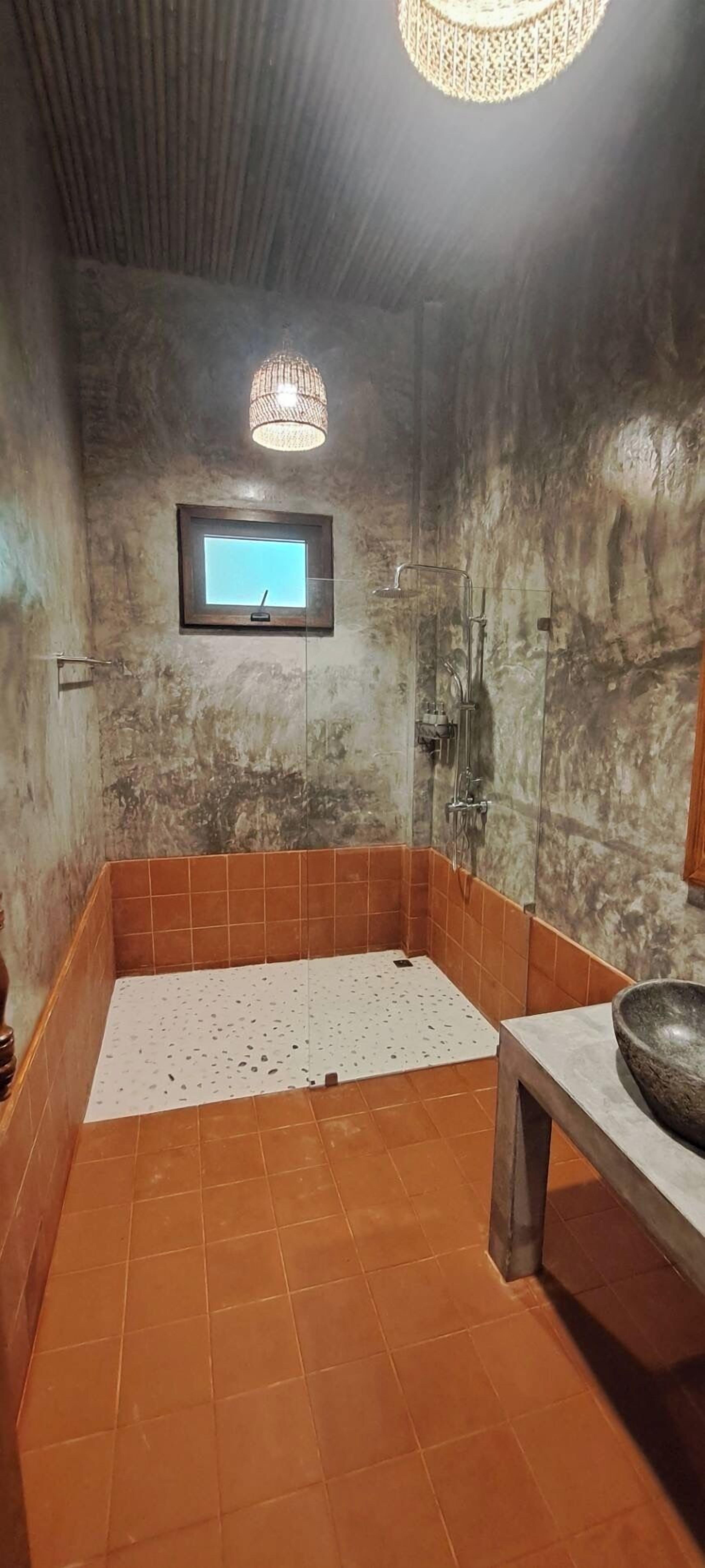 Un baño con ducha, lavamanos y ventana.